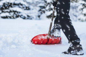 Person shoveling show with red shovel in blizzard